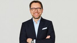 In the picture, you can see Stefan Rummel, CEO of Messe München Group, wearing a suit and smiling.