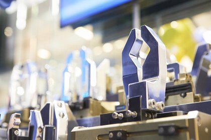 Close-up of industrial robot grippers in a factory environment, with metallic and blue components.