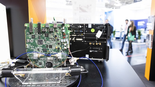 Close-up of an electronic circuit board on display, wired to another device.