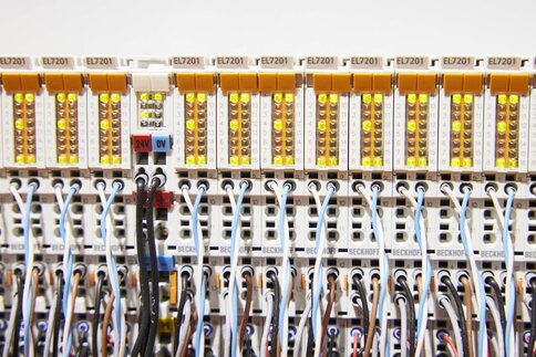 Close-up of an electrical switchboard with wires and bright yellow indicator lights.