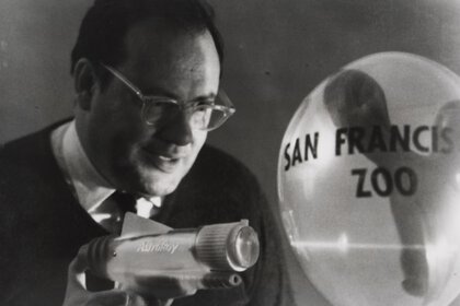 Schwarzweißfoto von einem Mann, der einen Laser auf einen Ballon mit der Aufschrift 