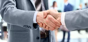 Close-up of a handshake between two people in business attire.