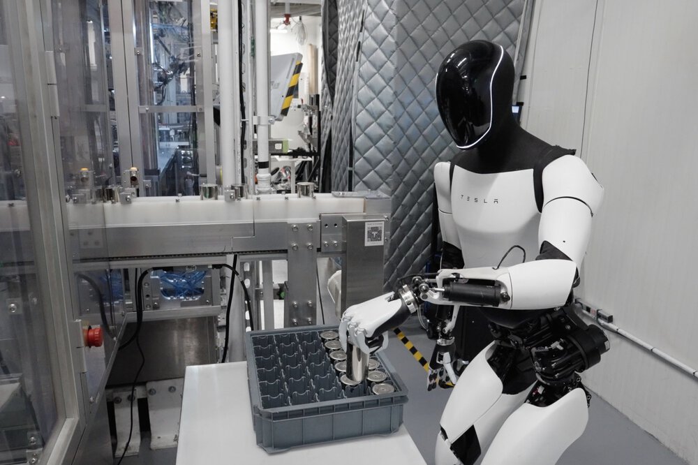 In a laboratory environment, a white humanoid robot sorts metal cylinders into a box.