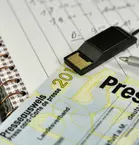 A press pass on a desk with a notepad and other paraphernalia.