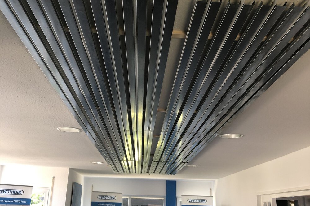 An der Decke montierte Metallschienen mit eingefädelten Schläuchen, in einem modernen Ausstellungsraum.