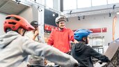 Radfahrer und Zuschauer bei einer Fahrradveranstaltung in einer Halle.