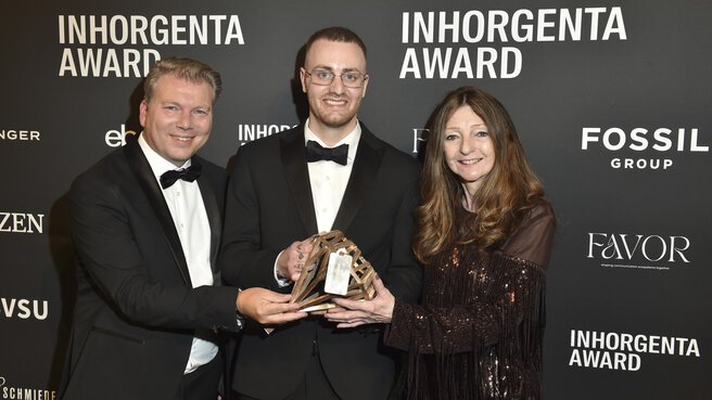Three smiling people hold the trophy for the “Design Newcomer of the Year” category in front of a logo wall at the INHORGENTA AWARD Gala.