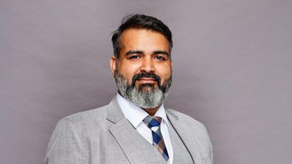 Bhupinder Singh in a grey suit.