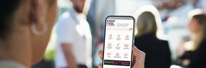 Eine Frau sieht sich die App der EXPO REAL am Smartphone an
