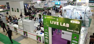 A lively exhibition hall with various stands and a large green LIVE LAB sign at analytica Vietnam.