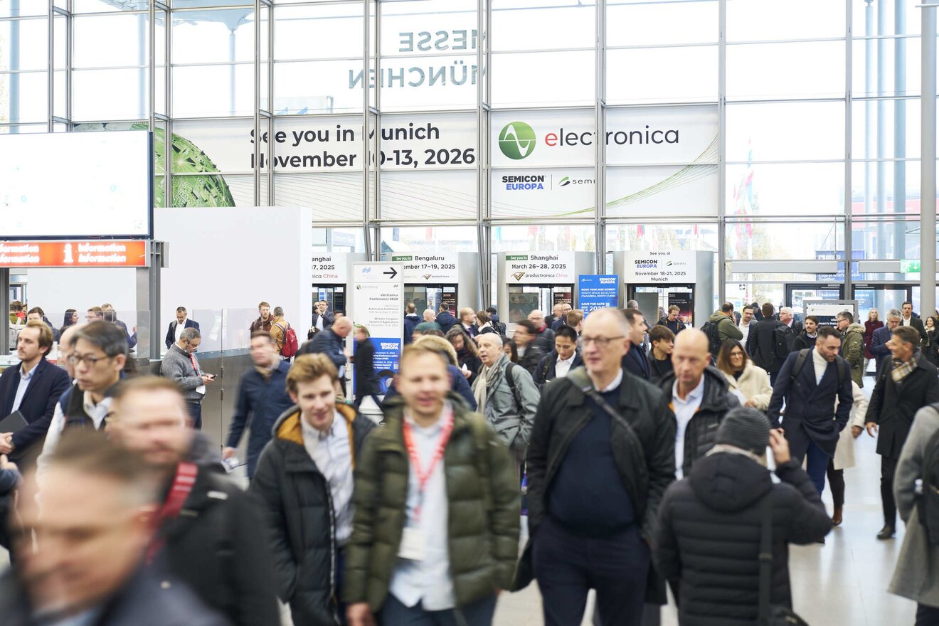 Auf dem Foto ist eine große Gruppe von Menschen zu sehen, die gemeinsam in eine Messehalle strömt, um die Fachmesse electronica zu besuchen.