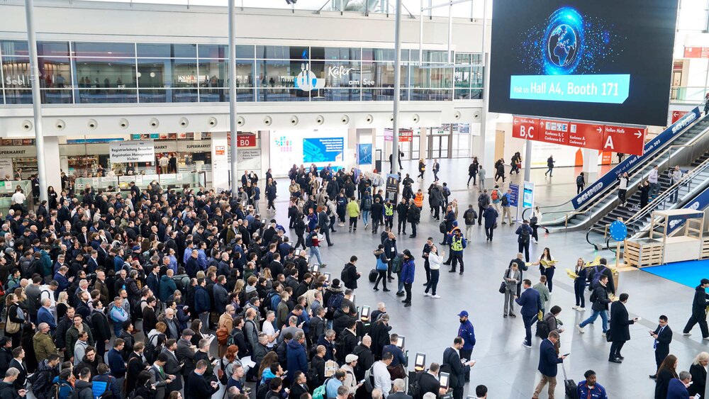 Zahlreiche Messebesucher stehen in langen Schlangen vor den Ticketkontrollen in einer Eingangshalle zur productronica.