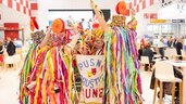 A group of people stands in a circle, surrounded by colorful crepe paper streamers