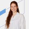 Porträt einer jungen Frau mit langen gewellten Haaren in weißer Bluse vor einem hellen Hintergrund mit blauen grafischen Linien