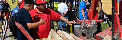  Two men look at a red log splitter at INTERFORST on the outdoor exhibition grounds of Messe München.