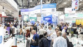 Crowded analytica exhibition hall with busy visitor traffic, laboratory and analytical technology booths, and large overhead banners.