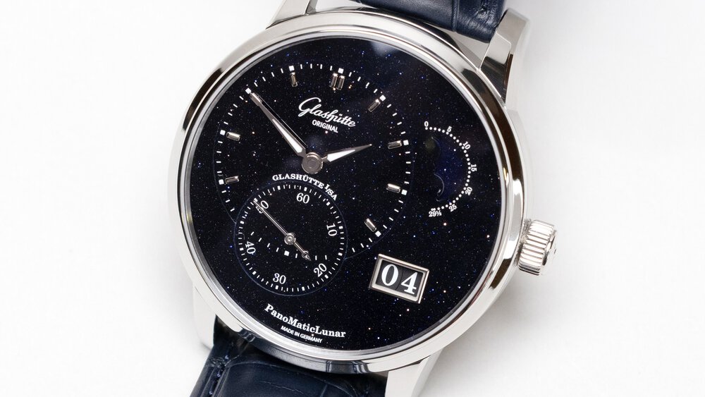 Close-up view of a delicate wristwatch with black straps, a dial with a starry background, and a day display.
