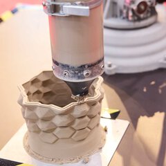 3D printing of a ceramic vase with visible layers during the printing process.