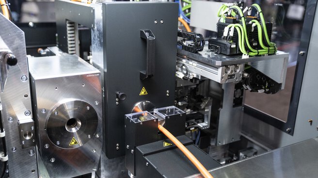 Industrielle Maschine steht zu Demonstrationszwecken auf der productronica. Ein orangenes Kabel ragt heraus.