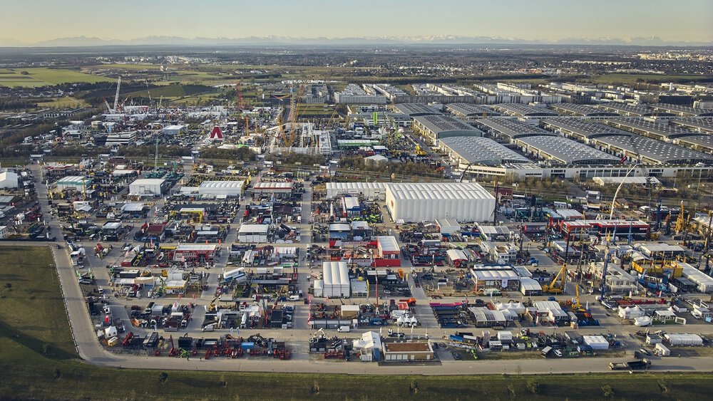 Aerial view of a large industrial area with numerous buildings, vehicles and equipment. Mountains can be seen in the background.