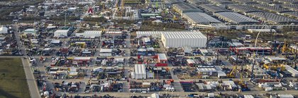 Aerial view of a large industrial area with numerous buildings, vehicles and equipment. Mountains can be seen in the background.