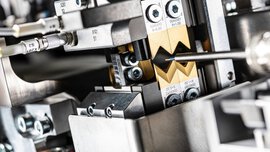 A close-up of a silver metal electronic device with a wire inserted between a pair of two gold prongs.