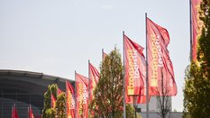 Viele rote Fahnen mit dem Logo der transport logistic wehen vor dem Eingang zur Messe München.