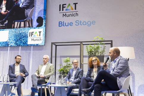 Fünf Personen sitzen zur Podiumsdiskussion auf der Blue Stage der IFAT Munich.