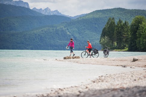 Zwei Radfahrende genießen den Blick auf den Walchensee vor der Kulisse der Bayerischen Alpen.