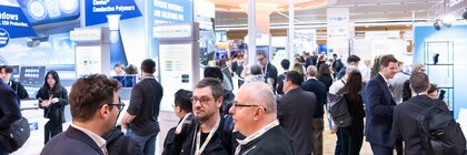 Trade visitors networking at booths showcasing conductive polymers and printed electronics at LOPEC