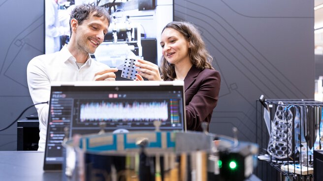 Zwei Fachbesucher begutachten gedruckte Elektronik im Gespräch am Messestand