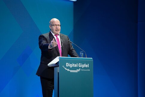 Mann im Anzug, der hinter einem Podium mit der Aufschrift 