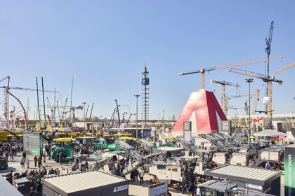 Freigelände der bauma 2025 mit vielen Kränen, Maschinen und Besuchern unter klarem, blauem Himmel.