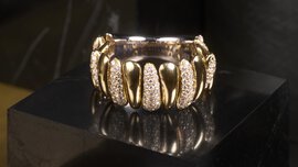 Goldring mit diamantbesetzten Segmenten auf schwarzer, glänzender Oberfläche.