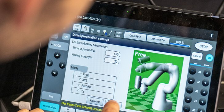 Hand bedient einen Touchscreen zur Steuerung eines Roboterarms mit grafischer Benutzeroberfläche und Einstellungsoptionen.