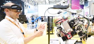 Trade fair visitor wearing AR glasses controls a robotic exhibit at the Laser World of Photonics 2025 in Munich.