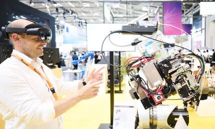 Messebesucher steuert mit AR-Brille ein robotisches Exponat auf der Laser World of Photonics 2025 in München.
