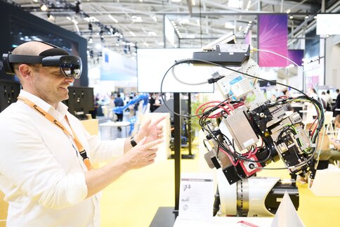 Messebesucher steuert mit AR-Brille ein robotisches Exponat auf der Laser World of Photonics 2025 in München.