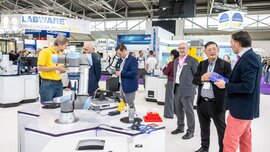 A group of international visitors chatting at the laboratory booth.