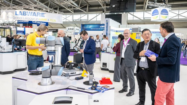 A group of international visitors chatting at the laboratory booth.