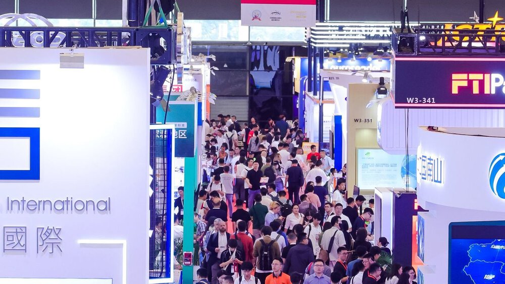 Numerous visitors to transport logistic CHINA walk across a red carpet laid out between many colourful exhibition stands.