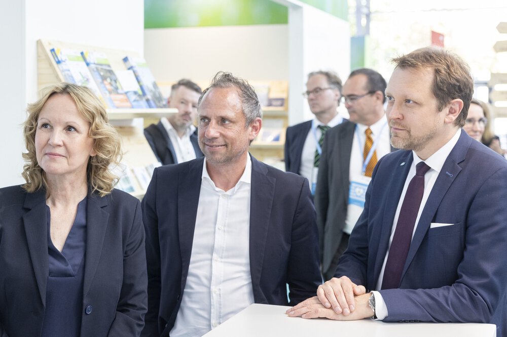 A group of people in business attire are smiling and looking to the left with interest.