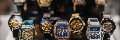 Nahaufnahme von Luxus-Armbanduhren in verschiedenen Stilen und Farben auf einem schwarzen Ständer.