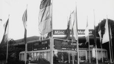 Schwarzweißfoto von Fahnen und Schildern vor dem Eingang der Messe LASER 83.