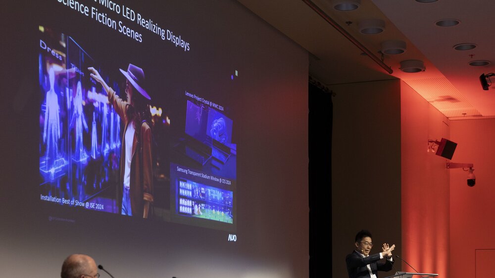 Ein Mann an einem Podium hält einen Vortrag zu dem Thema „Transparent Micro LED Realizing Displays in Science Fiction Scenes“.