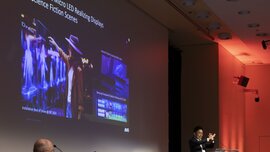 Ein Mann an einem Podium hält einen Vortrag zu dem Thema „Transparent Micro LED Realizing Displays in Science Fiction Scenes“.