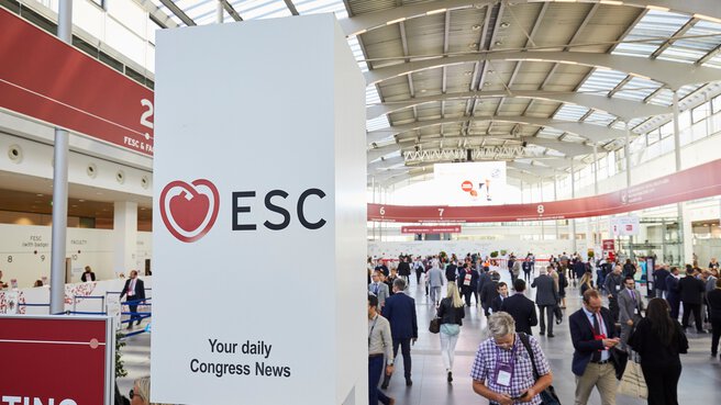 Blick in eine hohe Halle mit gewölbtem Dach während des ESC Congress mit zahlreichen Besuchern, die in unterschiedliche Richtungen laufen.