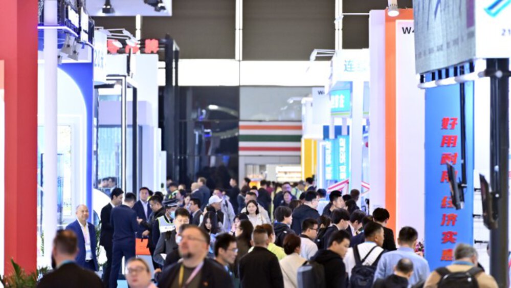 Numerous visitors to Messe München Shanghai walk past various colourful exhibition stands and trusses.
