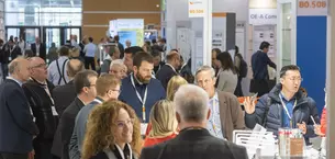 A well-filled exhibition hall with interacting visitors and a group standing around a stand.