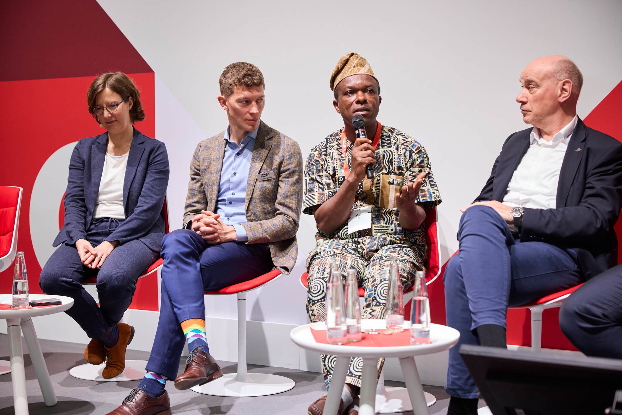 Podiumsdiskussion mit vier Teilnehmenden, einer spricht ins Mikrofon.